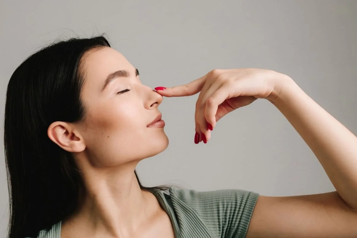 femeie care isi atinge nasul, fotografiata din profil